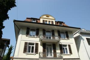 ein hohes weißes Gebäude mit Balkon darüber in der Unterkunft Swiss Holidays Apartment Rosenstrasse 10 in Interlaken