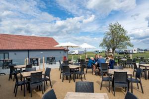 een groep mensen die aan tafels en stoelen zitten bij Camping Pods, Seaview Holiday Park in Whitstable