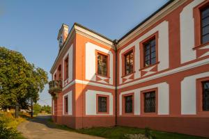 ein orangefarbenes und weißes Gebäude mit einem Baum in der Unterkunft Zámek Lobeč in Lobeč