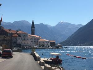 a boat on the water next to a town with mountains at Be happy in Perast in Perast