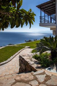a stone pathway leading to a house with the ocean in the background at Aegean Panorama Apartments in Akhladherí