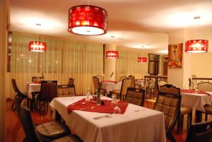 um restaurante com mesas e cadeiras brancas e lustres vermelhos em Churchill Addis Ababa Hotel em Addis Ababa