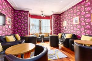 a waiting room with couches and tables and pink wallpaper at Valentine Lodge Over 25 Couples Only in Blackpool