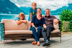 eine Familie, die auf einer Couch vor einem See sitzt in der Unterkunft Superior Hotel Nidwaldnerhof in Beckenried