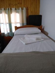 Una cama blanca con dos toallas blancas. en Cabañas Nativa en Montecarlo