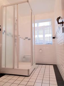 a bathroom with a shower and a tiled floor at Klara Guesthouse in Ólafsfjörður