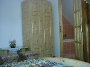 1 dormitorio con 1 cama y armario de madera en Lila Akác Vendégház, en Dabrony