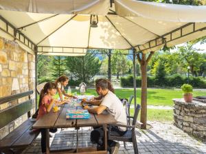 een man en twee kinderen aan een tafel onder een paraplu bij Ninemia Stay and Play in Karpenisi