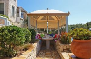 a pavilion with a table and an umbrella in a garden at Opera House Paxos in Gaios