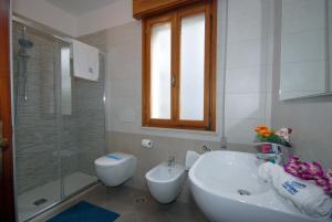 a white bathroom with a toilet and a sink and a shower at Appartamenti Las Palmas in Lignano Sabbiadoro