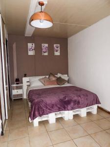 a bedroom with a large bed with a purple blanket at Sur la route du Voile in Salazie