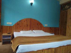 a bedroom with a large bed with a blue wall at Homestay Near Club House in Manāli