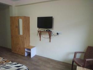 a bedroom with a flat screen tv on a wall at Homestay Near Club House in Manāli