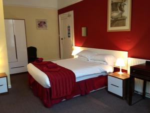
a hotel room with a bed, desk, and lamp at Abbey Lodge Hotel - B&B in London
