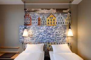 a bedroom with two beds and a painting on the wall at ibis Landshut City in Landshut