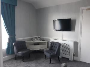 um quarto com duas cadeiras e uma televisão na parede em New Hall Bank em Bowness-on-Windermere
