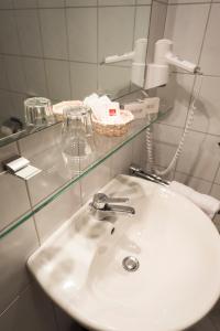 ein weißes Waschbecken im Bad mit Spiegel in der Unterkunft Hotel Dreisonnenberg in Neuschönau