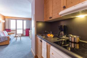 a kitchen with a stove top oven next to a living room at Résidence Pierre & Vacances L'Ours Blanc in L'Alpe-d'Huez