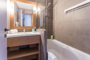 a bathroom with a sink and a tub and a mirror at Résidence Pierre & Vacances L'Ours Blanc in L'Alpe-d'Huez