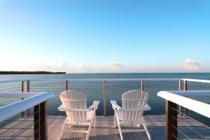 Dos sillas blancas sentadas en una terraza con vistas al agua en Isla Bella Beach Resort & Spa - Florida Keys, en Marathon