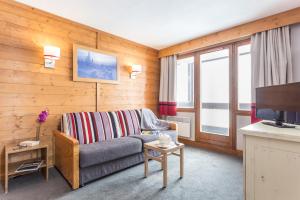 a living room with a couch and a television at Résidence Pierre & Vacances L'Ours Blanc in L'Alpe-d'Huez