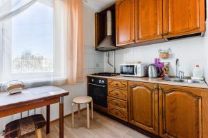 a kitchen with wooden cabinets and a sink and a microwave at Apartments on Volgina in Moscow