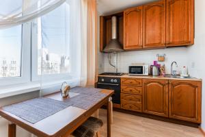 une cuisine avec des placards en bois, une table et une fenêtre dans l'établissement Apartments on Volgina, à Moscou