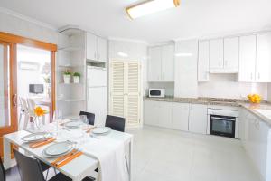 a white kitchen with a white table and chairs at Record Maritim II in Port d'Alcudia