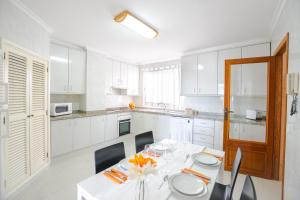 a white kitchen with a white table and chairs at Record Maritim II in Port d'Alcudia