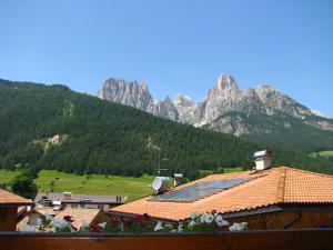 a group of buildings with mountains in the background at Hotel Nès Crépes in Pozza di Fassa