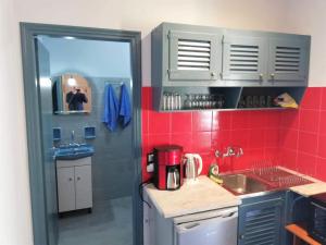 a small kitchen with a sink and red tiles at Issos Apartments in Corfu