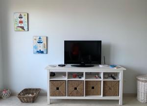a tv on a white stand in a room at Charming Beach Holiday Apartment in Lozenets