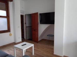 a living room with a table and a tv on a wall at Sofia's Flat in Valencia