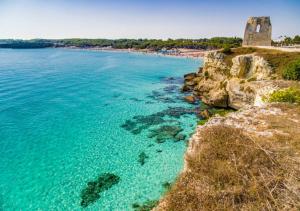 Blick auf einen Strand mit einem Schloss und das Meer in der Unterkunft Villetta M&M a Torre dell'Orso in Torre dell'Orso