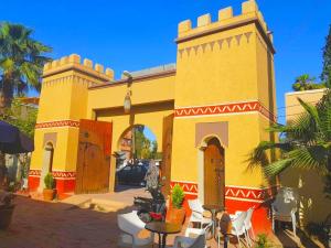a yellow and red building with tables and chairs at Riad Taroudant Palmiers in Taroudant