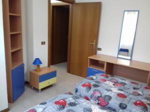 1 dormitorio con cama, escritorio y espejo en Appartamento Gioia (piano terra) en Asís