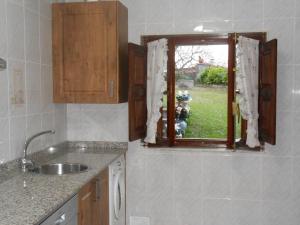 uma cozinha com um lavatório e uma janela com cortinas em La Bolerina em Celorio