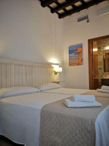 a bedroom with two beds with towels on them at Hostal La Fonda in Conil de la Frontera
