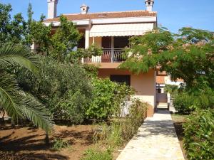 una casa con árboles y una pasarela delante de ella en Apartment Jadranka, en Olib