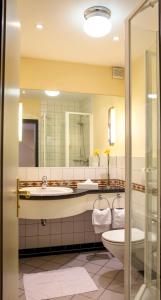 ein Badezimmer mit einem Waschbecken, einem WC und einem Spiegel in der Unterkunft Hotel Zur Post in Waldbreitbach