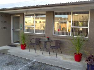 a patio with chairs and a table in front of a house at Almond Court Motel in Alexandra