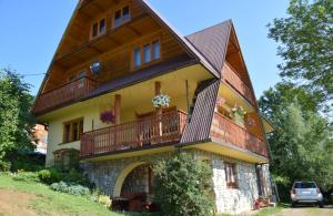 Cette grande maison dispose d'un balcon en bois sur le côté. dans l'établissement Na ubocy, à Brzegi