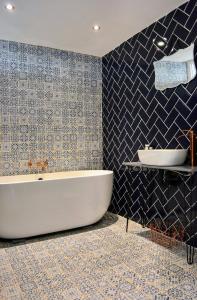 a bathroom with a tub and a blue tiled wall at The Space at 8, garden flat close to town & beach in Whitstable