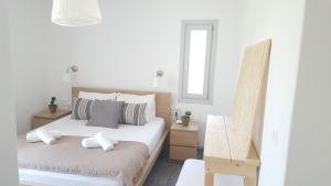 a white bedroom with two beds and a chair at Akrotiri Villas Skyros in Skiros