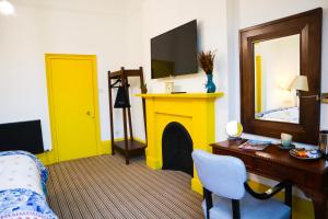 a living room with a yellow fireplace and a tv at New Town Guest House (Adults Only) in Edinburgh
