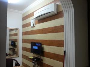 a room with a striped wall with a television on it at Beit Almurooj Hotel Apartment in Salalah