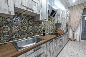 een keuken met een wastafel en een tegelwand bij Eco Apartments in french quarter in Kiev