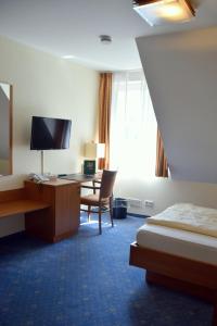 a hotel room with a desk and a bed at Gasthof Waldesruh in Saerbeck