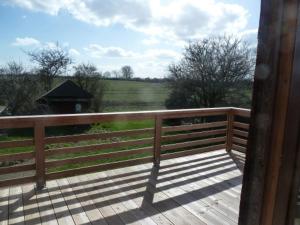 a wooden porch with a fence and a view of a field at Muschel in Riepsdorf