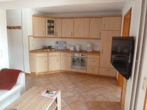 uma cozinha com armários de madeira e piso em azulejo em Muschel em Riepsdorf
